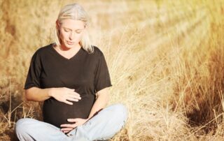 a pregnant woman sitting outdoors