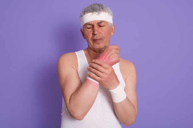 an old man dressed in active wear experiencing chronic wrist pain