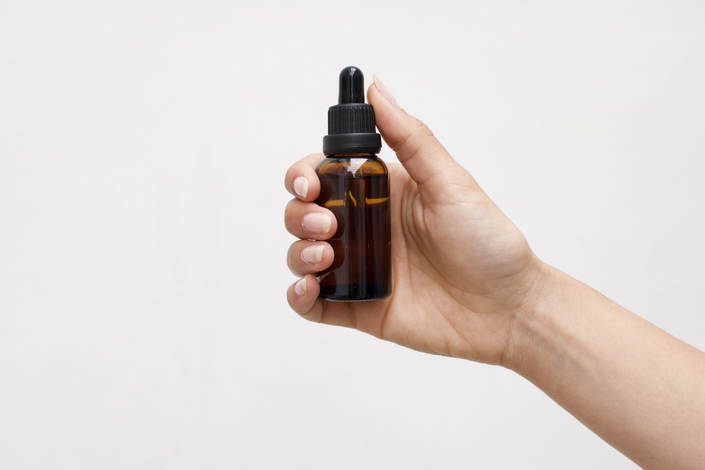 An individual holding a CBD oil bottle.