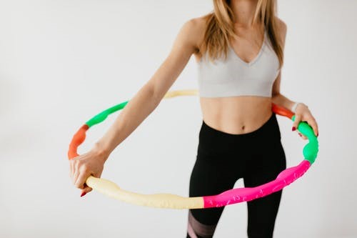 A thin, fit woman holds a hula hoop for exercise purposes.