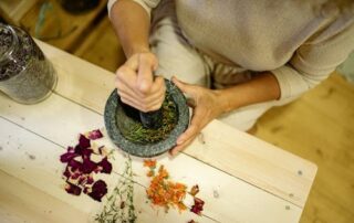 A person mixes medical-grade marijuana with other plants and herbs.