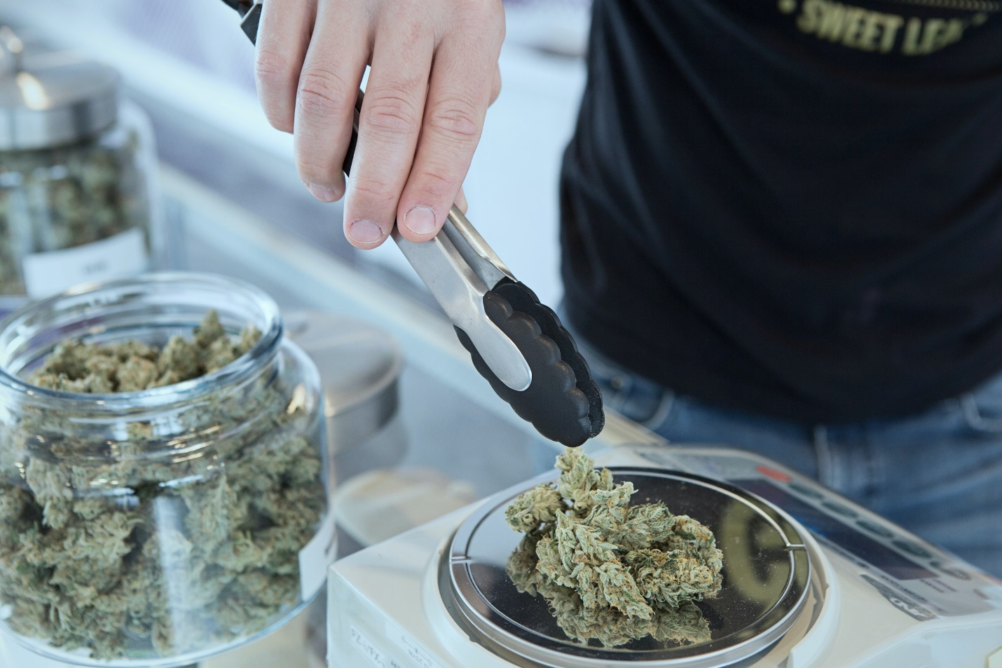 Close-up of person’s hand holding tongs and kush.