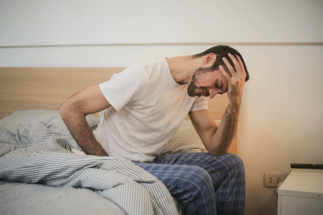 A person holding their head in bed