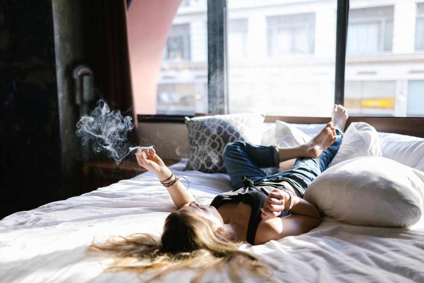 a woman lying on bed and smoking marijuana