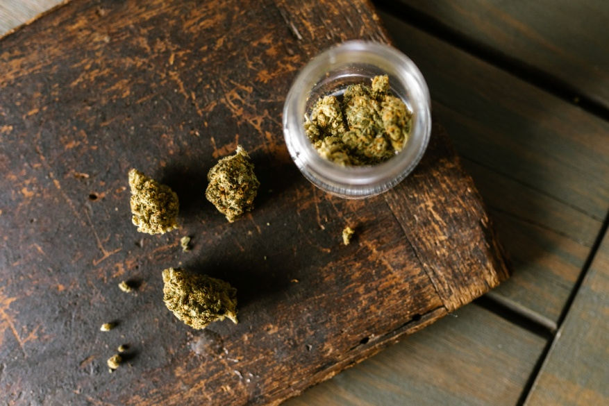 marijuana placed on a wooden plank and in a glass container