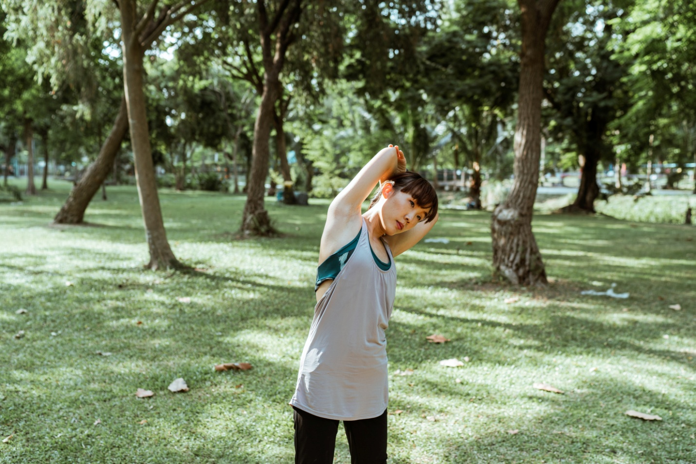 Woman stretching muscles of arm and back in park